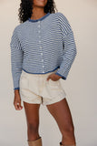 Person wearing a blue and white striped shirt and beige shorts against a plain background