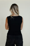 Person wearing a black sleeveless top and black pants against a plain background