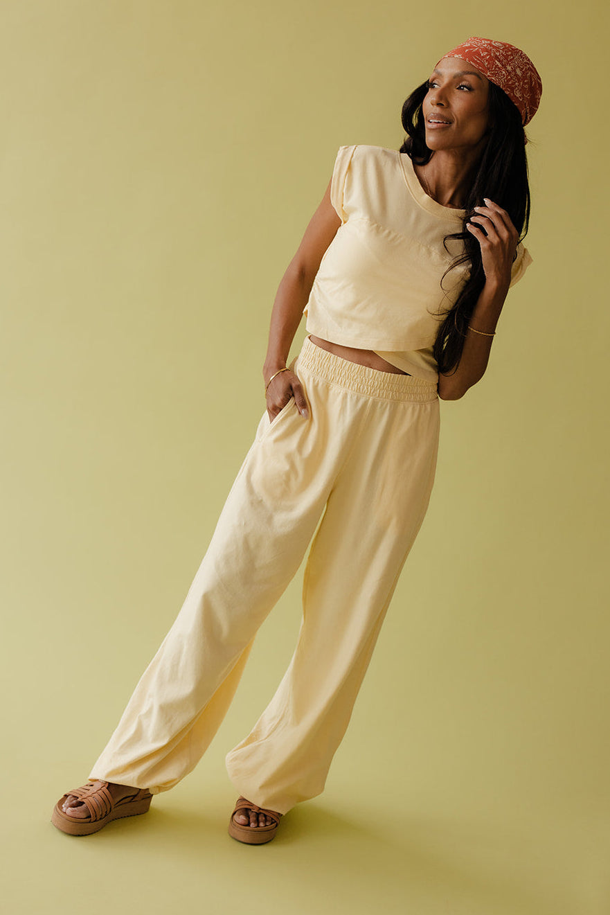Woman in a beige outfit with a red headband on a yellow background