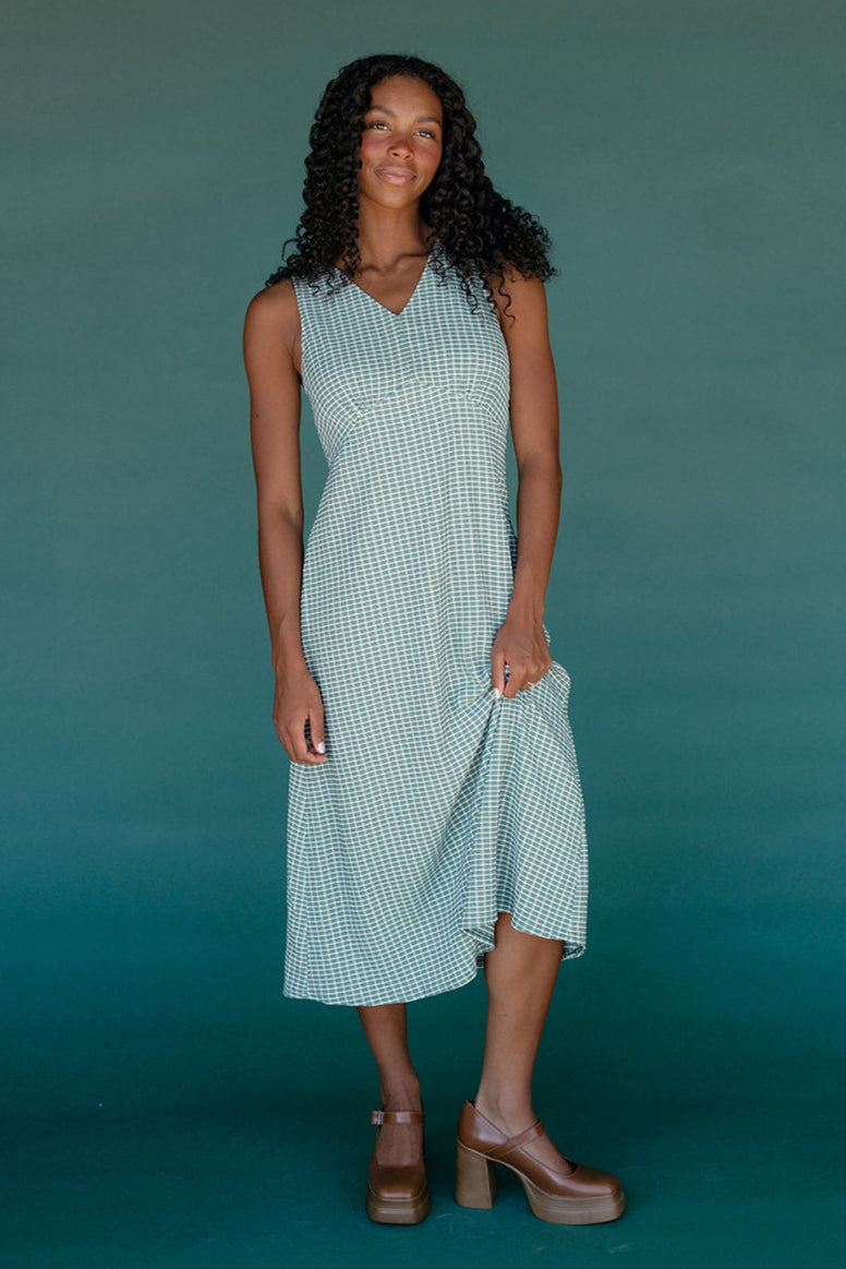 Woman wearing a green checkered dress against a teal background