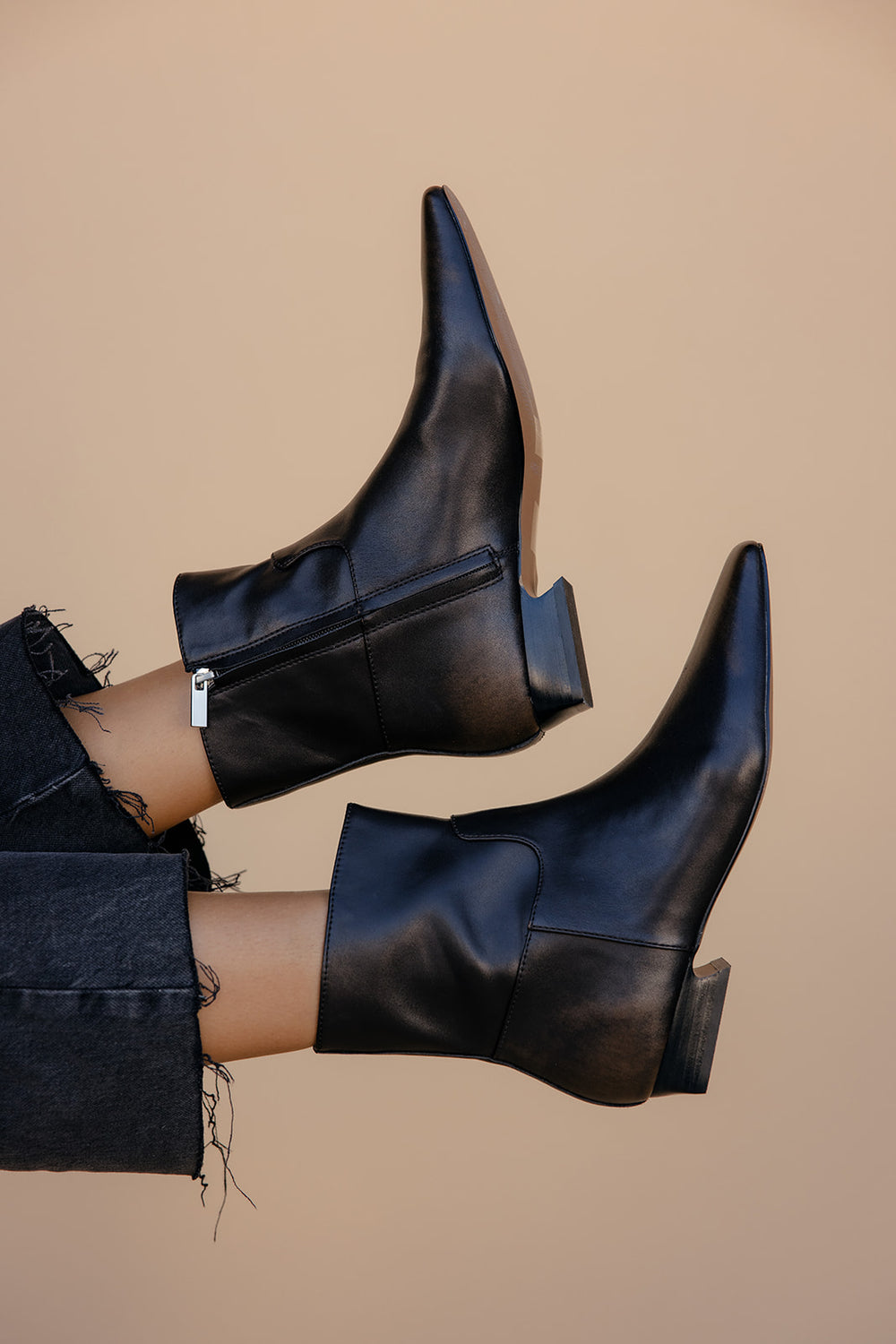 Brown leather ankle boots worn with a beige background