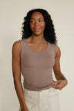 Woman wearing a brown tank top against a plain background
