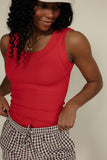 Woman wearing a red sleeveless top and checkered pants against a plain background