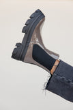Gray sandal with black sole worn by a person on a light gray background