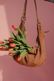 Brown suede handbag with red tulips against a pink background
