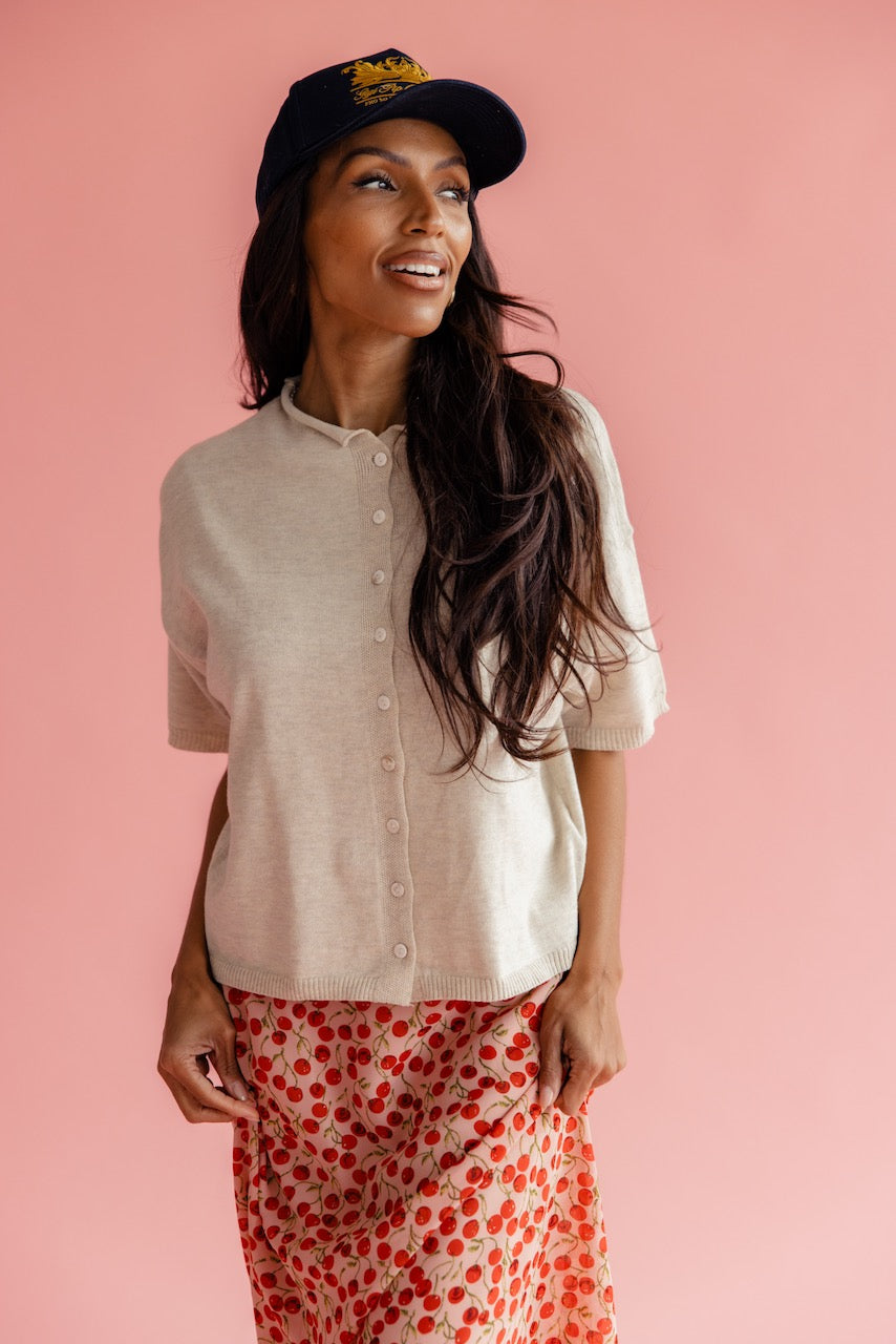 Women wearing a button up cardigan and cherry print skirt