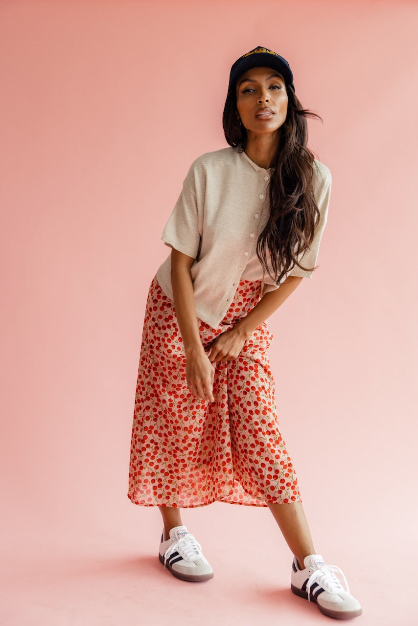 Women wearing a tan sweater and red print skirt